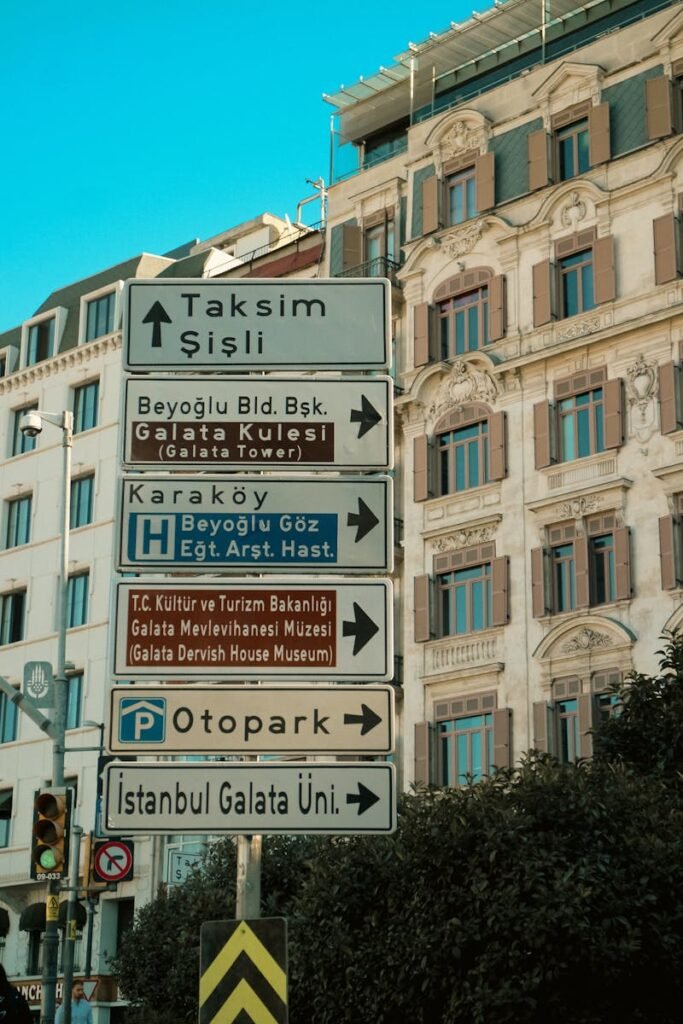 Signposts in Istanbul pointing toward Galata Tower and Beyoğlu district, showcasing iconic architecture.