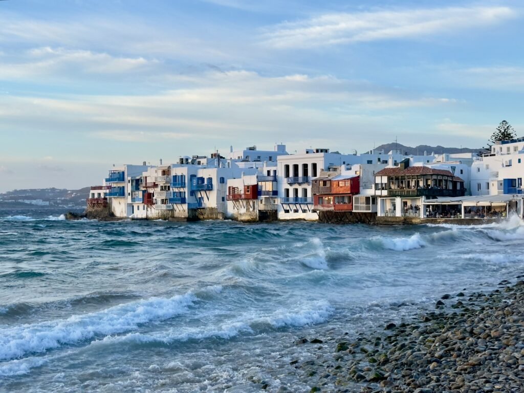 a row of houses sitting on top of a beach next to the ocean