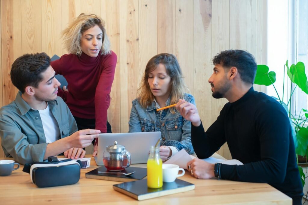 Diverse team brainstorming with laptop in a modern office setting.